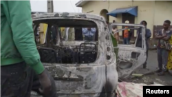FILE - In this image taken from video, people observe the aftermath of an attack by armed militants in Cameroon's South West region on Sept. 9, 2023. The militants stopped cars, shot at passengers and set vehicles ablaze in the village of Muea, killing at least two people.