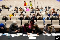 FILE - Refugees that fled the war in Ukraine fill in the paperwork to get registered, at the congress center in Prague, Czech Republic, March 15, 2022.