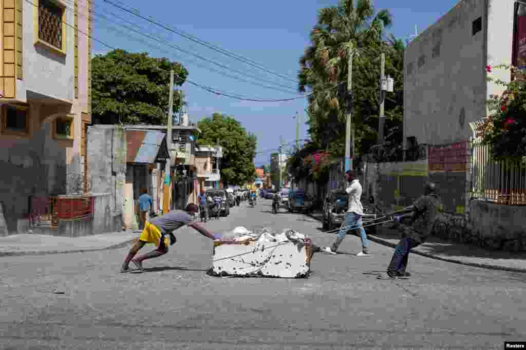 Men move a dead body inside an old refrigerator in Port-au-Prince, Haiti, June 30, 2024.