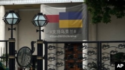 A paramilitary policeman stands watch at the Polish Embassy, which displays a banner showing support for Ukraine, in Beijing, May 17, 2023. 