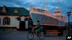 A boy rides a bicycle in what used to be the main port of Aralsk, Kazakhstan, before the Aral Sea dried up, July 4, 2023. 