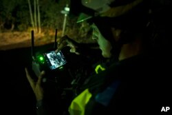 A firefighter uses a drone near the fire advancing through the forest toward the town of El Rosario in Tenerife, Canary Islands, Spain, Aug. 18, 2023.