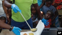 FILE - A server ladles soup as children line up to receive food at a shelter for families displaced by gang violence, in Port-au-Prince, Haiti, March 14, 2024.