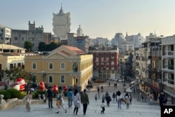FILE - Tourists enjoy unusual tranquility at the historic site Ruins of St. Paul's in Macao, Dec. 28, 2022.
