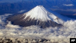 FILE - Mount Fuji, Japan's highest peak at 3,776 meters, is seen from an airplane window, Dec. 8, 2010. Those who want to climb one of the most popular trails of the iconic mountain will now have to make a reservation and pay a fee.