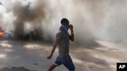 A man walks past burning tires set on fire by protesters to call attention to the country's insecurity and demanding the resignation of the prime minister, in Port-au-Prince, Haiti, Jan. 18, 2024.