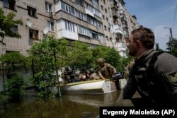 FILE - Ukrainian servicemen arrive by boats to evacuate people in a flooded neighborhood in Kherson, Ukraine, Thursday, June 8, 2023. (AP Photo/Evgeniy Maloletka)