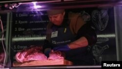 A vendor chops meat as she waits for customers in a small store during a power outage after critical civil infrastructure was hit by Russian missile attacks, in Kharkiv, Ukraine, March 9, 2023.
