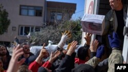 FILE - Residents grab food, clothes and household items delivered from the back of a truck in Samandag, south of Hatay, Turkey, Feb. 16, 2023, ten days after a 7.8-magnitude quake struck the border region of Turkey and Syria. 