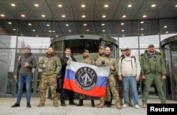 FILE - Visitors pose outside PMC Wagner Center, which is a project implemented by the founder of the Wagner private military group, Yevgeny Prigozhin, during the official opening of the office block in Saint Petersburg, Russia, Nov. 4, 2022.