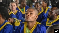 Marcel Malanga, center, sits in court in Kinshasa with 52 other defendants June 7, 2024, accused of a role in last month's attempted coup in Congo.