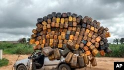 A driver carrying empty plastic containers pauses on his way to buy fuel from Angola and sell it back in Muanda, western Democratic Republic of Congo, Dec. 23, 2023. 