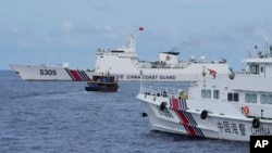 FILE — A Philippine supply boat, center, steers around Chinese coast guard ships trying to block its way near Second Thomas Shoal, Aug. 22, 2023. Two Philippine supply boats breached a Chinese coast guard blockade in the South China Sea on Oct. 4, 2023.
