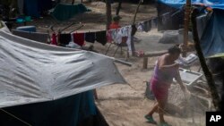A migrant sweeps the ground at a shelter encampment in the border town of Matamoros, Mexico, Aug. 16, 2023. 