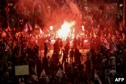 Relatives and supporters of hostages taken captive by Palestinian militants in Gaza during the Oct. 7 attacks, light flares and wave national flags during a demonstration calling for their release, in the Israeli city of Tel Aviv on April 27, 2024.