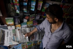 Newspaper hawker arranges papers published in the region at his shop. (Wasim Nabi/VOA)