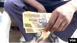 FILE - A street vendor holding Zimbabwe's outgoing currency in Harare in April 2024. (Columbus Mavhunga/VOA)