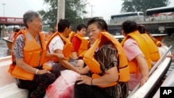 In this photo released by Xinhua News Agency, residents are rescued by boat in the flood-hit Fangshan district on the outskirts of Beijing, Aug. 2, 2023. 