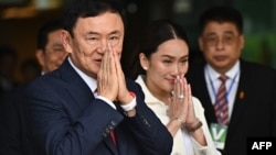 Mantan Perdana Menteri Thailand Thaksin Shinawatra menyapa pendukungnya bersama putri bungsunya Paetongtarn Shinawatra (kanan) setelah mendarat di Bandara Don Mueang Bangkok pada 22 Agustus 2023. (Foto: AFP)