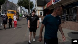 Guided by trainer Vasyl Hoshovskyi, foreground, Denys Abdulin, a former Ukrainian soldier, learns to navigate the streets of Rivne, Ukraine.