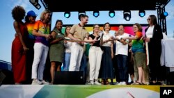French Sports Minister Amelie Oudea-Castera, center, in dark skirt, takes part in the opening of Pride House, a safe space for the LGBTQ+ community of athletes, during the 2024 Summer Olympics, in Paris, France, July 29, 2024. 