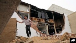 A man walks over bricks that tumbled from a damaged building in the aftermath of a severe thunderstorm in Houston, Texas, May 17, 2024.