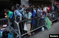 Des migrants récemment arrivés à New York attendent sur le trottoir à l'extérieur de l'hôtel Roosevelt dans le centre-ville de Manhattan, États-Unis, le 1er août 2023.