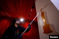Seorang pekerja mengecat dinding dekat dekorasi berbentuk piala Oscar. Persiapan masih terus berlangsung jelang Oscar 2023 di Dolby Theatre, Los Angeles, 9 Maret 2023 (Foto: Eric Gaillard/Reuter)