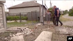 FILE - This image taken from a video shows people indicating a damaged building in the Belgorod region, Russia, May 22, 2023.