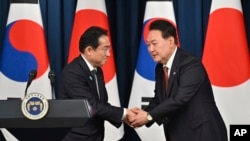 South Korean President Yoon Suk Yeol, right, shakes hands with Japanese Prime Minister Fumio Kishida during a joint press conference after their meeting at the presidential office in Seoul, May 7, 2023. 