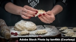 FILE - Woman makes a delicious Ukrainian national food, varenyky with raspberry. (Adobe Stock Photo by tan4ikk)