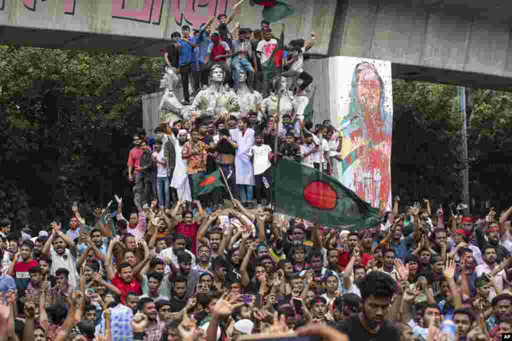 Protesters climb a public monument as they celebrate the news of Prime Minister Sheikh Hasina&#39;s resignation, in Dhaka, Aug. 5, 2024.