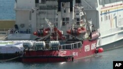 This image from video shows a ship belonging to Spanish aid group Open Arms, background, and a barge docked at Larnaca port in Cyprus, March 11, 2024. World Central Kitchen posted on X that the ship, loaded with some 200 tons of food, set sail on March 12.