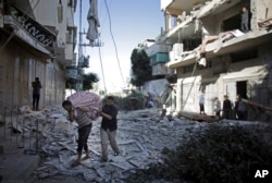 FILE - Palestinians salvage what they can of their belongings from the rubble of their destroyed house following an early morning Israeli missile strike in Gaza City, July 16, 2014.