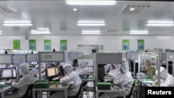 FILE - Employees work at a production line inside a factory exporting cameras used in mobile phones to Africa, in Shenyang, Liaoning province, China, Oct. 18, 2013.