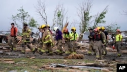Firefighters walks among tornado-damaged homes, in Greenfield, Iowa, May 21, 2024.