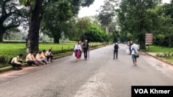 មគ្គទេសក៍ទេសចរ​មួយ​ចំនួន​អង្គុយ​រងចាំ​ភ្ញៀវនៅ​មុខ​បរិវេណ​នៃ​ប្រាសាទ​អង្គរវត្ត នៅ​ខេត្ត​សៀមរាប​ កាលពី​ថ្ងៃទី ៣ ខែតុលា ឆ្នាំ ២០២៣។ (ធីតា វីន/វីអូអេ) 