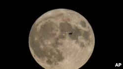 Sebuah pesawat terbang di depan bulan di Chicago, pada 30 Agustus 2023. (Foto: AP/Kiichiro Sato)