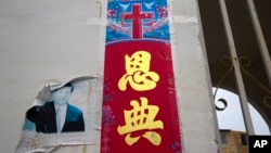 FILE - A faded photo of Chinese President Xi Jinping is seen near the Christian poster with the word 'Grace' outside a house church near Nanyang in central China's Henan province on June 1, 2018.