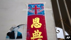 FILE - A faded photo of Chinese President Xi Jinping is posted near a Christian poster with the word "Grace" outside a house church near Nanyang, Henan Province, on June 1, 2018. The Patriotic Education Law, which took effect Jan. 1, 2024, targets religious teaching.