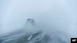 A truck moves along the snow-blown eastbound lane of US Highway 20 during a blizzard near Sac City, Iowa, Jan. 13, 2024.