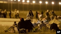 Migrants wait in the cold at a gate in the border fence after crossing from Ciudad Juarez, Mexico, into El Paso, Texas, in the early hours of May 11, 2023. 