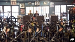 FILE - Salesmen Will Malfeld, left, and Ben Chandler work at University Bicycles in Boulder, Colo., April 30, 2024.