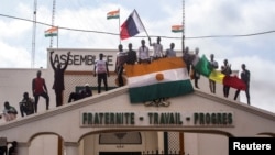Men hold Nigerien and Russian flags as they gather with thousands of anti-sanctions protesters in support of putschist soldiers in the capital Niamey, Niger, Aug. 3, 2023.