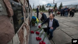 Chernobyl's nuclear power plant workers lay flowers at a monument to the victims of the 1986 explosion and fire at the plant in Chernobyl, Ukraine, April 26, 2023.