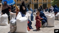 FILE - Afghan women receive food rations distributed by a humanitarian aid group, in Kabul, Afghanistan, May 28, 2023.