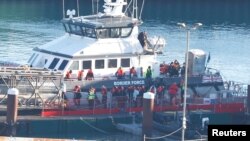 Orang-orang, yang diyakini sebagai migran, turun dari kapal Pasukan Perbatasan di pusat pemrosesan Pasukan Perbatasan, Dover, Inggris, 10 Desember 2022. (REUTERS/Peter Nicholls)