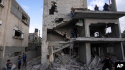 Palestinians inspect the rubble at the site of an airstrike that the Israeli military said targeted the house of an Islamic Jihad member, in central Gaza Strip, May 13, 2023.