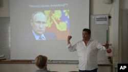 Masai Bjoerkwall, a junior high school teacher at Viktor Rydberg's School, teaches the history of NATO and the implications of Sweden joining NATO in Stockholm, Sweden, May 17, 2024. Slogan reads: 'Geopolitical disaster.'