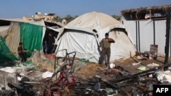 People stand in the midst of the destruction in the aftermath of a reported overnight Israeli strike that hit tents used as temporary shelters by displaced Palestinians in Deir el-Balah, central Gaza Strip, on August 4, 2024.